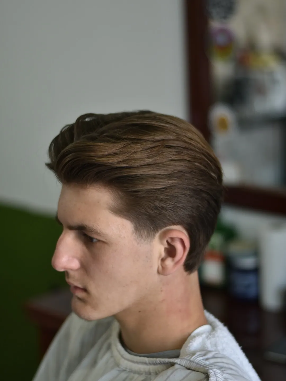 Cabelo médio penteado para trás com degradê suave nas laterais